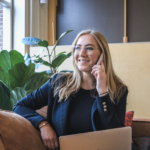 Frau telefoniert im Büro mit Laptop auf dem Schoß