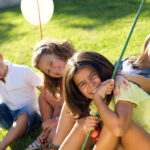 Vier Kinder im Sommer auf der Wiese. Kinderbetreuung Österreich Vergleich