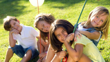 Vier Kinder im Sommer auf der Wiese. Kinderbetreuung Österreich Vergleich