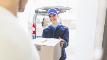 Eine Paketzustellerin liefert ein Paket aus. Ab Jänner bekommt sie um 16 Prozent höheres Gehalt.