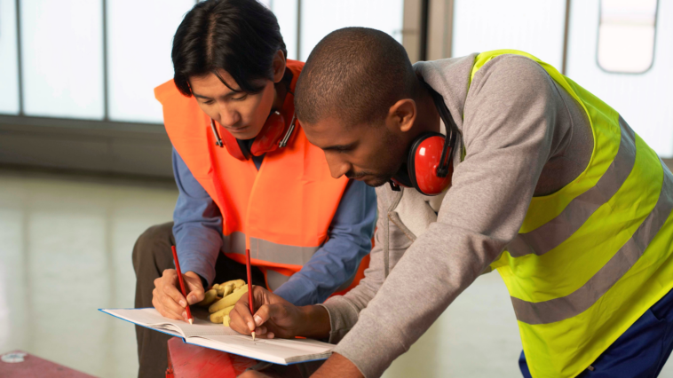 Zwei Arbeiter in einer Fabrik - durch den Sozialstaat Österreich sind sie auch bei Krankheit oder Kündigung abgesichert
