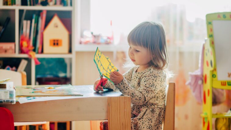 In Salzburg mangelt es an Kinderbetreuung. Auf dem Bild ist ein Kind zu sehen, das aus Papier ausschneidet.