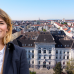 Bezirksvorsteherin Stefanie Lamp vor einer Aufnahme des Bezirksamtes Ottakring. Im Hintergrund rote Häuserdächer und ein paar Bäume.