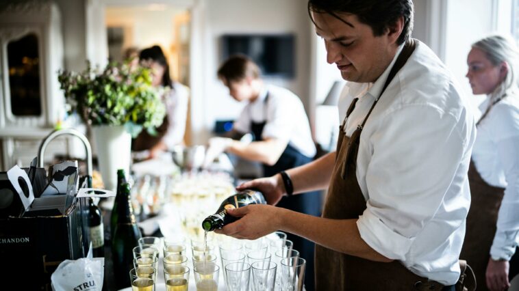 Kurz Martin Ho The Dots Group Lohnbetrug Kellner gießt Champagner in Gläser
