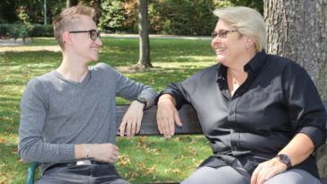 Die Bürgermeisterin von Schwechat, Karin Baier, plaidert auf einer Bank im Park mit einem Bürger.