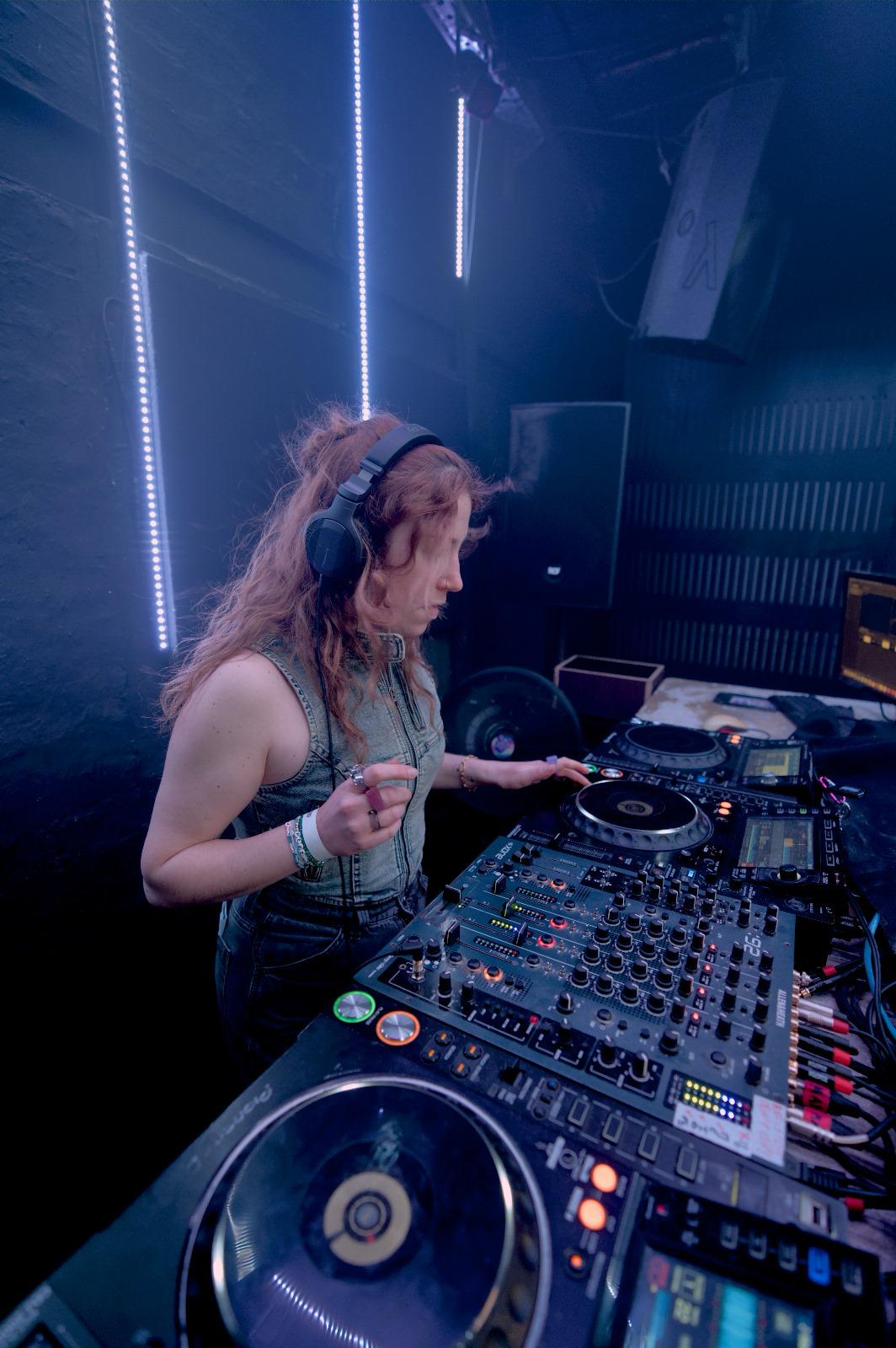 Eine Frau spielt Musik über ein DJ-Pult ab.