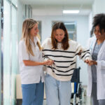 Auf dem Bild zu sehen ist ein Gang im Spital - 3 Frauen gehen in Richtung der Kamera und im Text geht es um die Bedeutung von Gendermedizin in Kärnten.