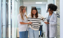 Auf dem Bild zu sehen ist ein Gang im Spital - 3 Frauen gehen in Richtung der Kamera und im Text geht es um die Bedeutung von Gendermedizin in Kärnten.