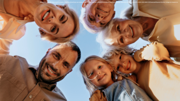 Die Armutsgefährdung im Burgenland sinkt erneut. Ob für die jüngere Generation oder die ältere - betreffen wird diese positive Entwicklung alle. Am Bild sind ein Vater, eine Mutter, zwei Großmütter und zwei Mädchen zu sehen, die im Kreis nach unten blicken, so als würden sie sich über ein Baby-Bett neigen.